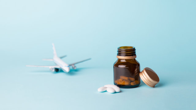 Airplane Model With White Pills From Motion Sickness Scattered From A Glass Jar On A Blue Background. Concept Nausea In The Plane