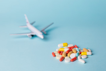 airplane model with multi-colored pills from motion sickness scattered on a blue background. concept nausea in the plane