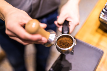 Fototapeta na wymiar Barista with tamper and piston, portafilter in front of a grinder making espresso.