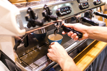Prepares espresso in his coffee shop with hand. close up