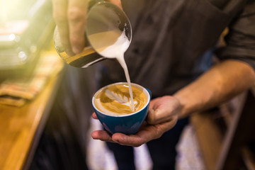Barista hands make coffee latte art with coffee espresso machine in coffee shop cafe