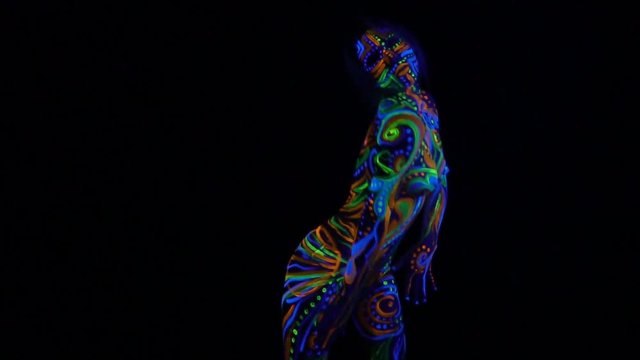 Young woman with bright ultraviolet body art, dancing in the dark
