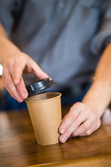 Fototapeta na wymiar Close up of a barista hands preparing coffee to go in coffee shop