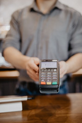 Barista hold card reader. Customer paying for their order with a credit card in a cafe. Bartender holding a credit card reader machine.