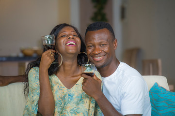 lifestyle home portrait of young romantic and happy black Afro American couple in love drinking wine cup at living room couch enjoying anniversary or Valentine