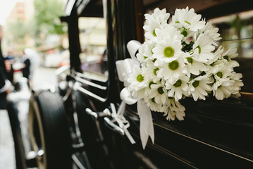 Bouquet of daisies decorating an antique wedding car.