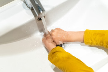 Responsible child cleaning his hands in a sink.
