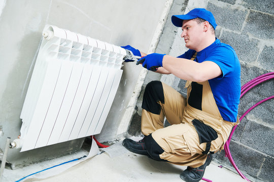 plumber at work. Installing water heating radiator