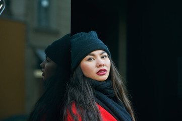 Portrait of a young beautiful fashionable woman in a red coat . Model posing on a city street