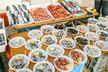 Open air street food fish market with raw fresh sushi ready to eat: shrimp, oyster, sea urchin, cuttlefish, squid, octopus and salpa, sole and various fish