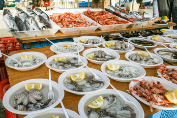 Open air street food fish market with raw fresh sushi ready to eat: shrimp, oyster, sea urchin,...