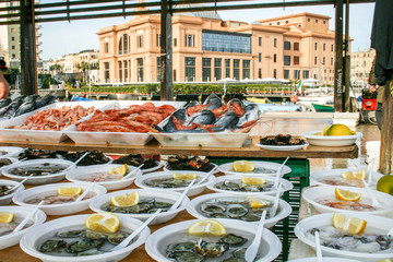 Open air street food fish market with raw fresh sushi ready to eat: shrimp, oyster, sea urchin,...