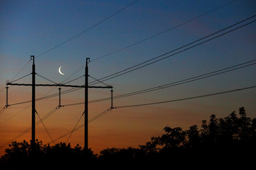 Fototapeta premium Electrical lines under a night sky with moon