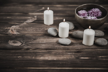Obraz na płótnie Canvas Singing bowl with candles with pebbles on dark wooden background