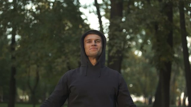 Happy man doing breathing exercises at park, body and mind harmony, sport