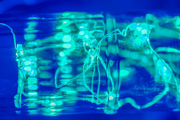 Magic blue and cold green light. Green garland in the bottle, abstract.