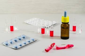 Ampoules with white and red liquid pills on a light background