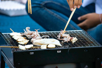 Fresh squid and mushrooms on the grill grate steel.