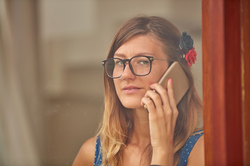 Young woman using smart phone indoors. Window reflection from outdoors.