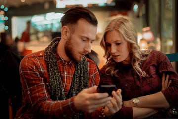 Young couple using the phone at the bar