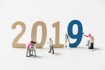 miniature people paint a wood number 2019 for happy new year on white background