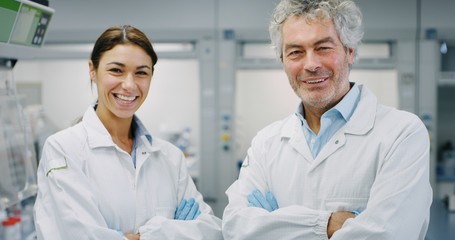 Obraz premium Portrait of two smiling scientists wearing protection glasses satisfied with a great results of completed research in laboratory. Concept: research,biochemistry, pharmaceutical medicine