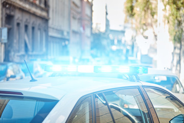 Police car with blue lights on the crime scene in traffic / urban environment.