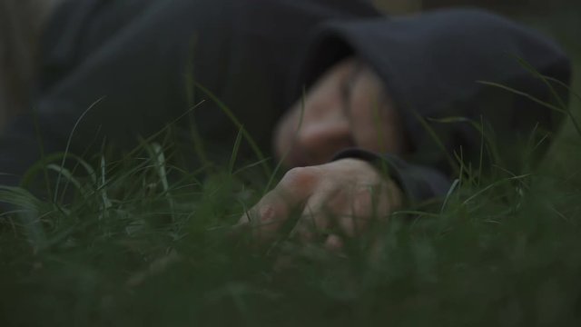 Victim of thugs lying on grass, mans corpse, murdered citizen, crime scene