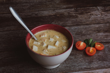 Vegetable pumpkin cream soup with crackers in a bowl with a spoon on a wooden table with parsley