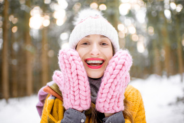 Close-up portrait of a young woman in bright winter clothes in pine forest. Skin care during the winter time concept