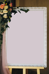 Guest list mockup. Stylish vintage board frame with space for text for guests seats and floral decorations at wedding reception in restaurant.