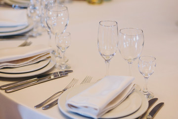 Stylish table with empty plates, glasses, cutlery, white napkin at wedding reception. Luxury catering and serving. Christmas and New Year feast. Celebrations and party concept.
