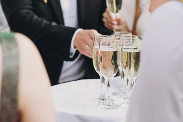 Waiter serving tray with champagne glasses for guests at wedding reception outdoors. Luxury life. Christmas and New Year feast.