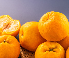 Beautiful and delicous tangerine isolated on airy blue background with bamboo sieve, new modern concept of chinese new year, close up, copy space