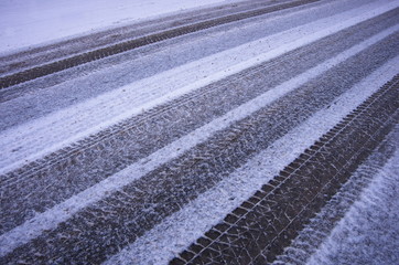 Abstract  background of car tracks on snow-covered road. Snow traces of the wheel of the car. Trace of the wheels on the snow as a background