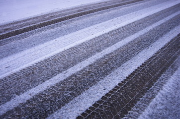Fototapeta premium Abstract background of car tracks on snow-covered road. Snow traces of the wheel of the car. Trace of the wheels on the snow as a background