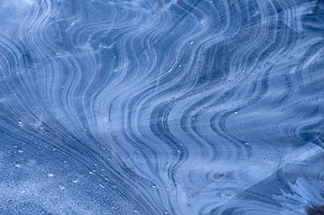 Ice pattern background on near the shore of the pond or river. Abstract patterns of ice formation. Ice patterns freezing water crystals. Blue ice texture
