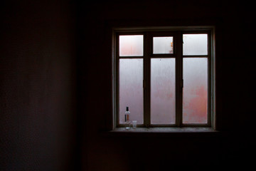 a lighted window in the black room of an abandoned house, a clear outline, glass covered with frost,