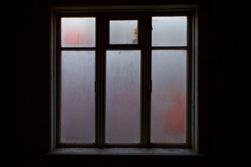 a lighted window in the black room of an abandoned house, a clear outline, glass covered with frost,
