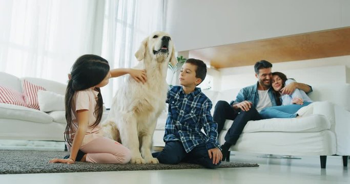 Portrait of happy family with a dog having fun together in living room in slow motion. Shot with RED camera in 8K. Concept of happy family, parenthood, love for animals