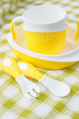 Set of yellow empty dishes for baby. Tableware for the first feeding, soft focus background