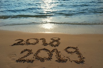 Happy new year concept, the year 2018 is going to pass 2019 is coming write on sand beach in sunrise.