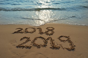 Happy new year concept, the year 2018 is going to pass 2019 is coming write on sand beach in sunrise.