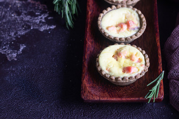 Mini tartlets with cream cheese filling and salmon on old brown background.