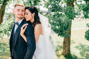 Beautiful wedding couple outdoor portrait. Young pretty bride hugging groom at nature.  Fine art...