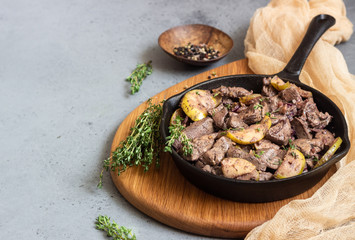 Fried chicken liver with apples, onions and thyme in a frying pan. 