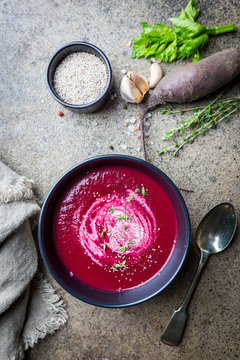 Cold Beetroot mashed soup with cream, apple, cheese and thyme in a dark bowl over stone background, top view.