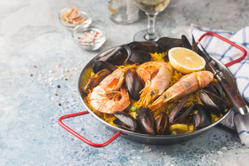Traditional spanish seafood paella in a fry pan with white wine