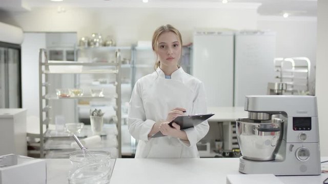 Young chef cook in professional uniform is using her tablet to make a list