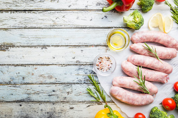 Raw Homemade Chicken Sausage with seasonings and vegetables over white wooden background